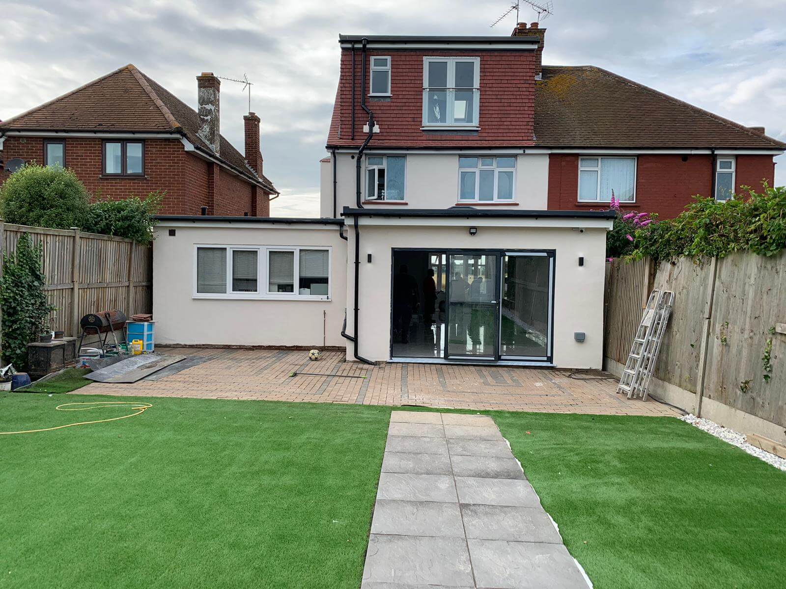 Completed rear house extension with black-framed doors and landscaped garden